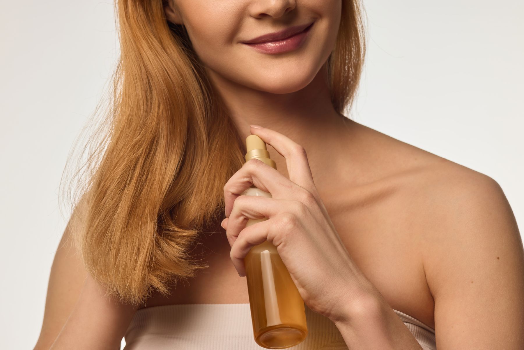 Woman using heat protective spray on hair