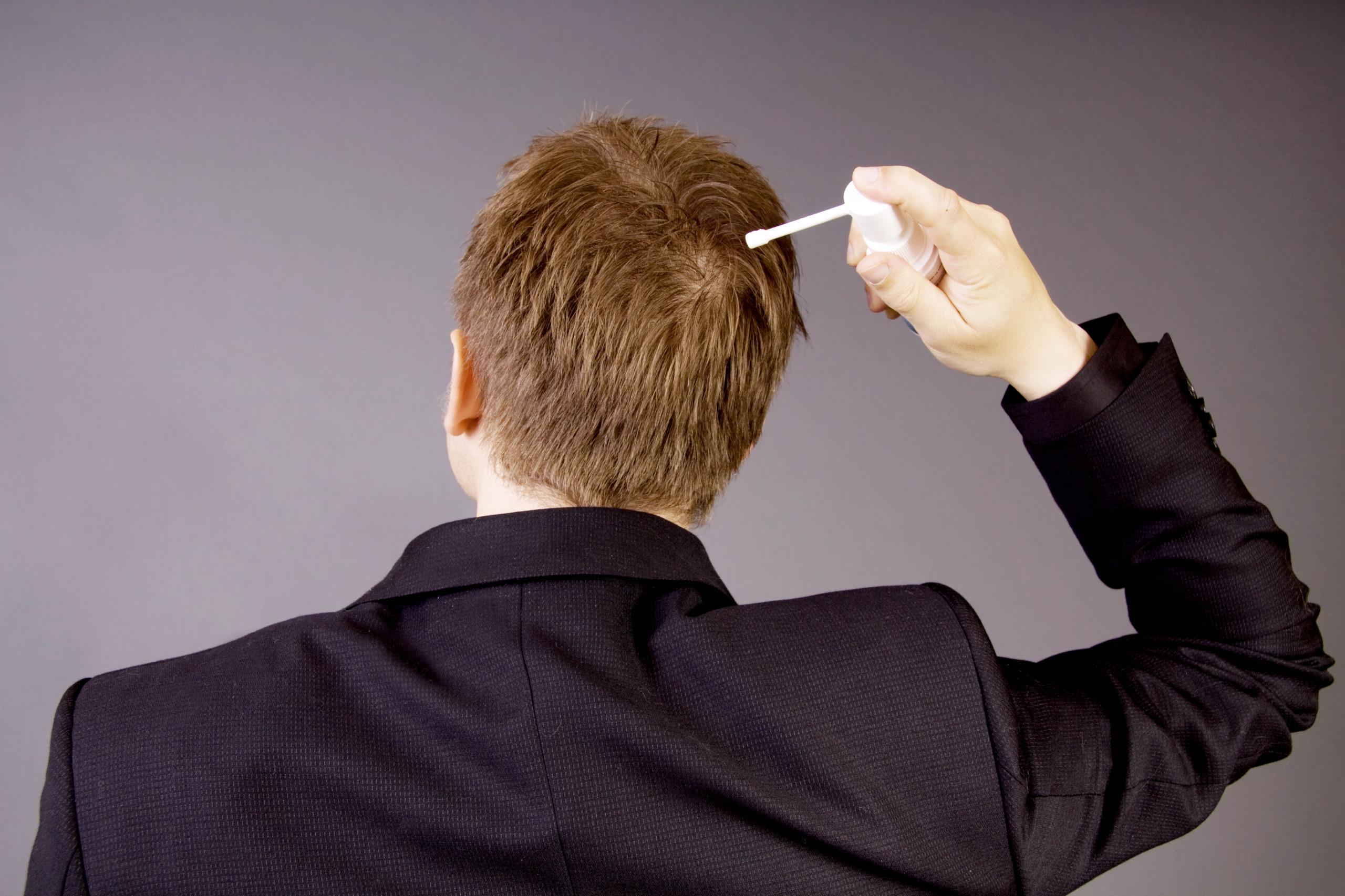 person applying a hair loss treatment to their scalp